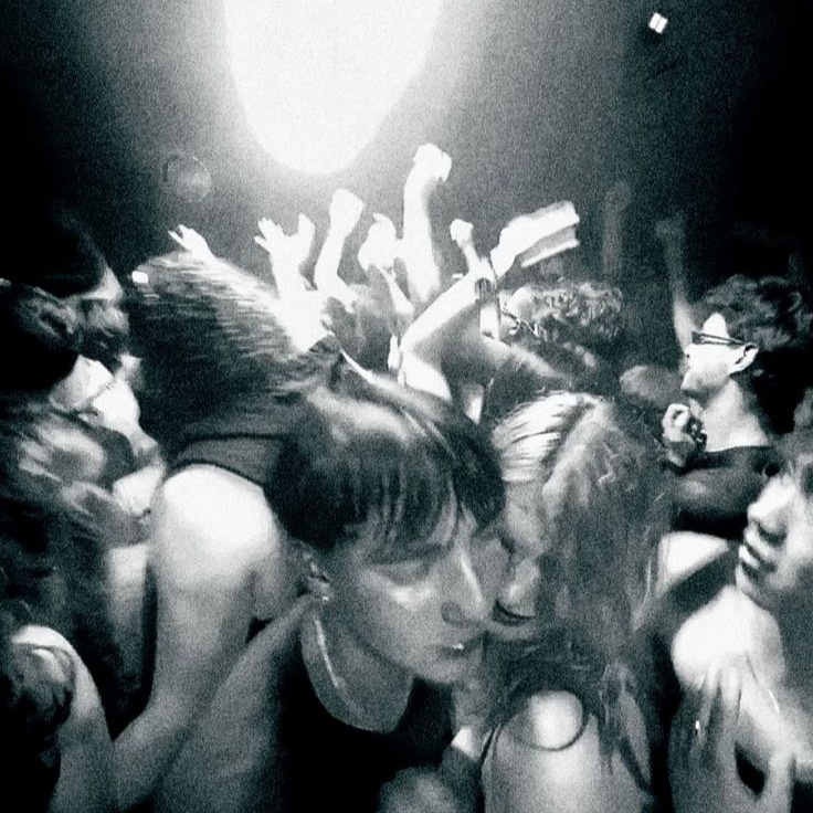 A packed dance floor under a single spotlight, hands raised in the dark
